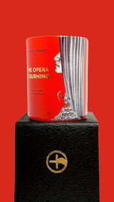 Red scented candle with 'The Opera is Burning' text and proprietary Créateur Olfactif illustrations on a red background